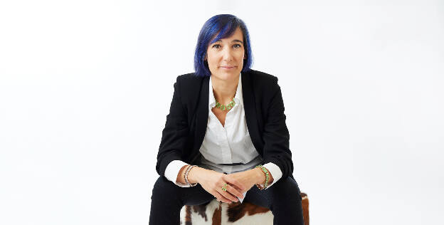 Businessportrait Frau vor weißem Hintergrund Frau mit blauen Haaren sitzt auf einem Hocker im Kuhfellmuster- Businessfotograf Businessfotografie Christian Vorhofer